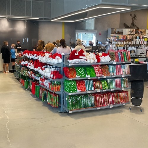 Retail checkout queue featuring EZI-Q® merchandising bays filled with Christmas-themed impulse products, with customers browsing festive items while waiting in line